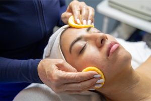 Woman receiving a facial treatment with citrus pads, showcasing skincare techniques at Luxe Aesthetic Center.